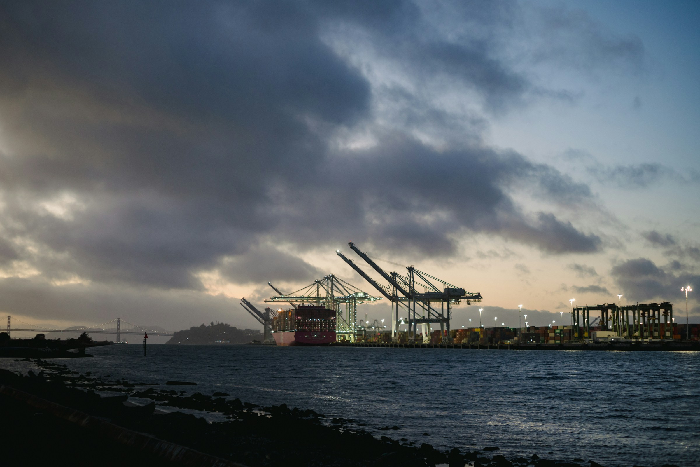 Gantry cranes and shipping containers at a port at dusk